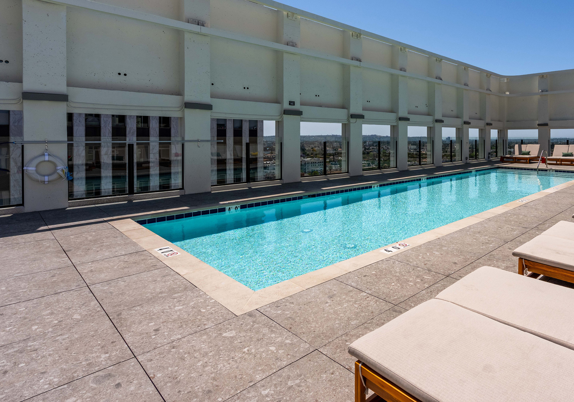 Rooftop deck with outdoor dining seating and BBQs with view of downtown Los Angeles skyline.